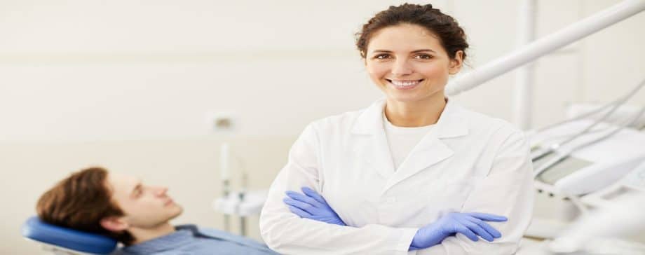 female dentist with male patient behind her in dental chair