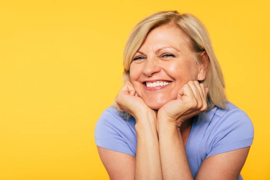 smiling woman in blue t-shirt with yellow background