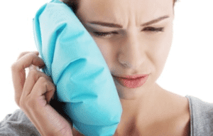 woman holding ice pack against jaw