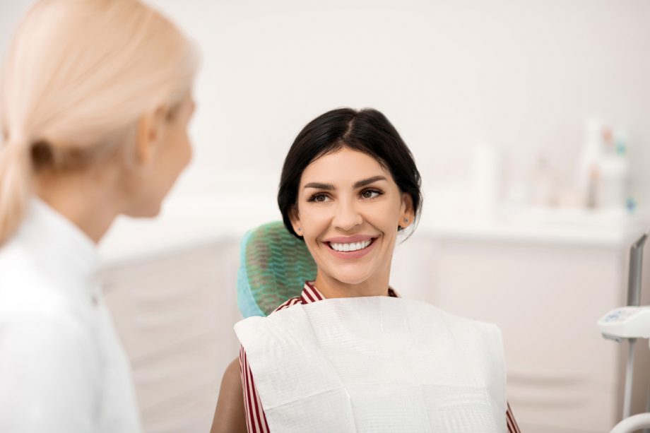 female patient in dental chair smiling at dentist
