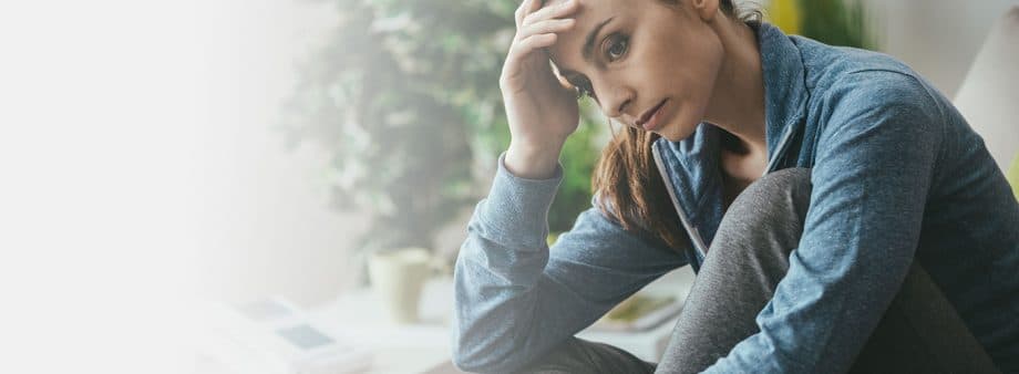 woman sitting on bed with head in hand