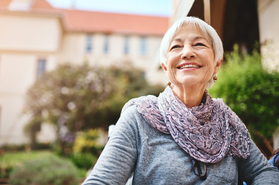 senior woman with short hair sitting outside, smiling