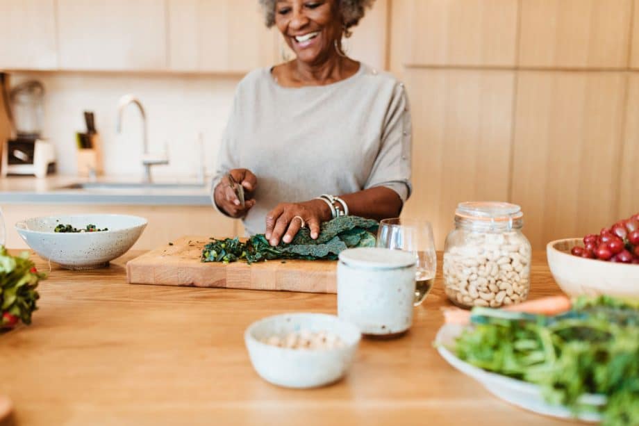 senior woman in kitchen chopping kale on cutting board
