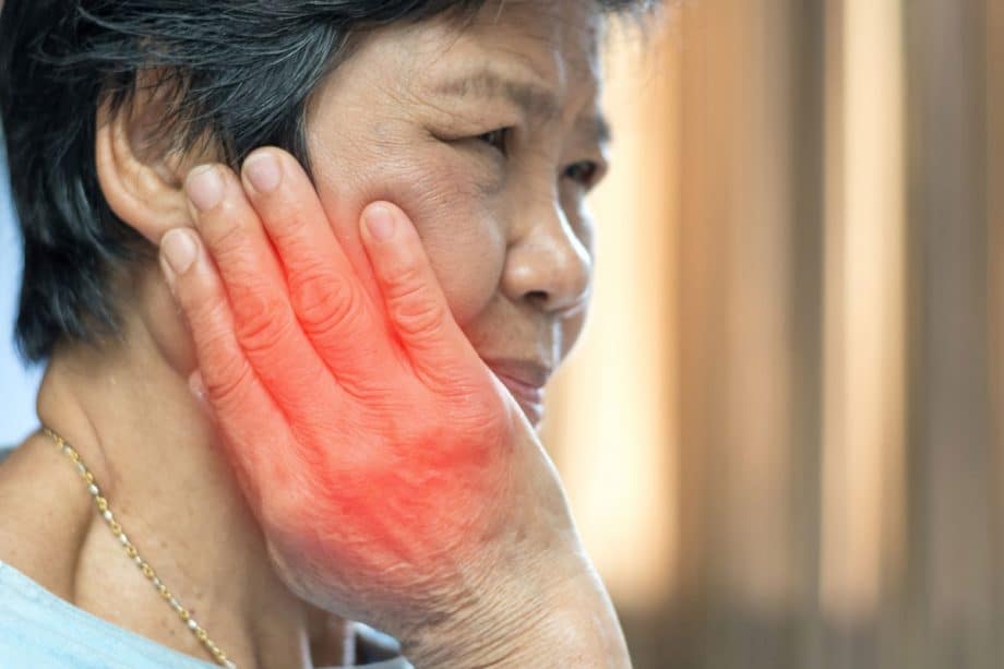 side profile of woman touching her jaw in pain